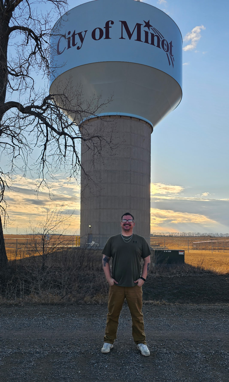 Eric Locken standing in front of the Minot water tower